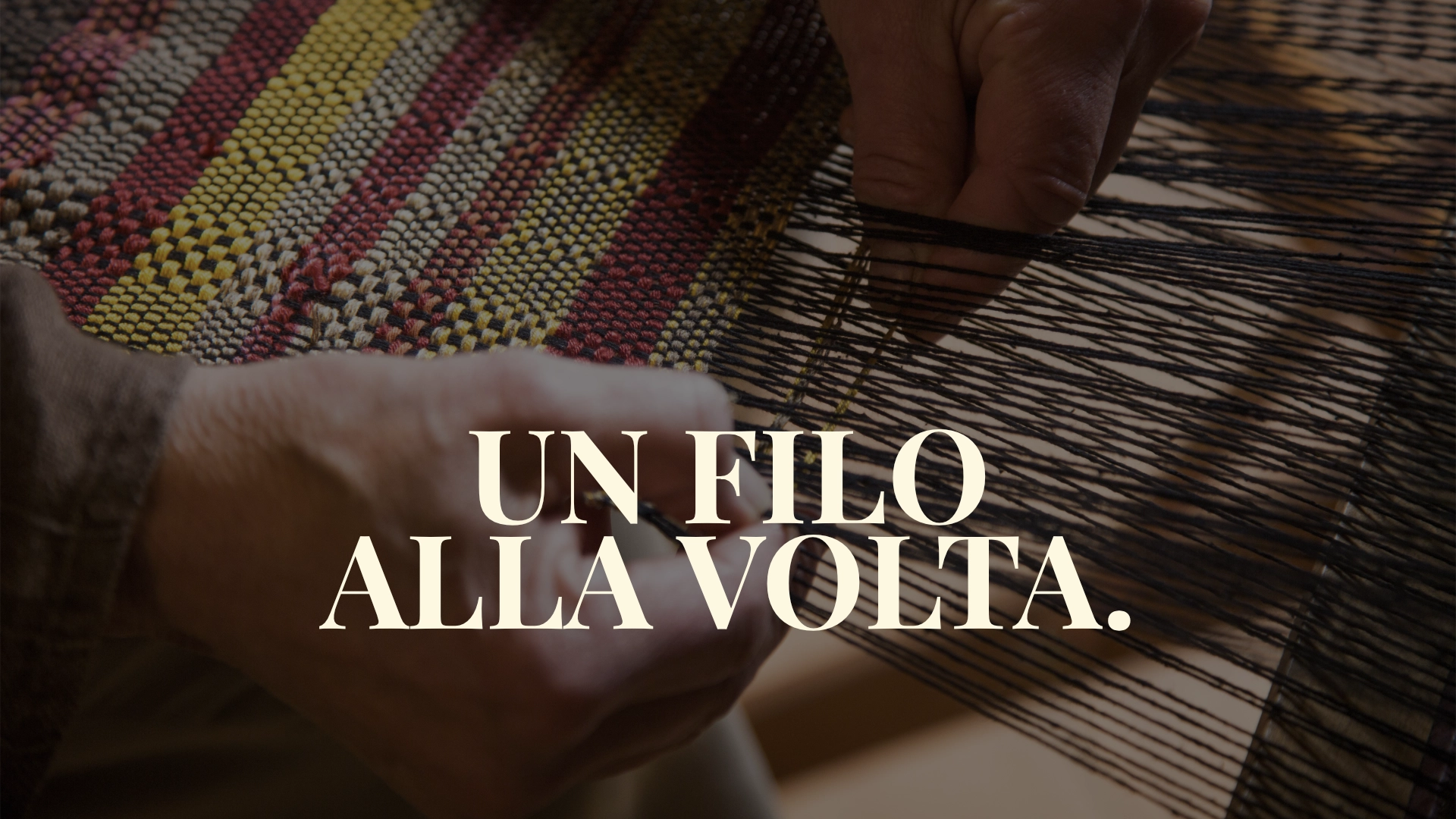 Foto di due mani che intrecciano trama e ordito con in evidenza la scritta un filo alla volta