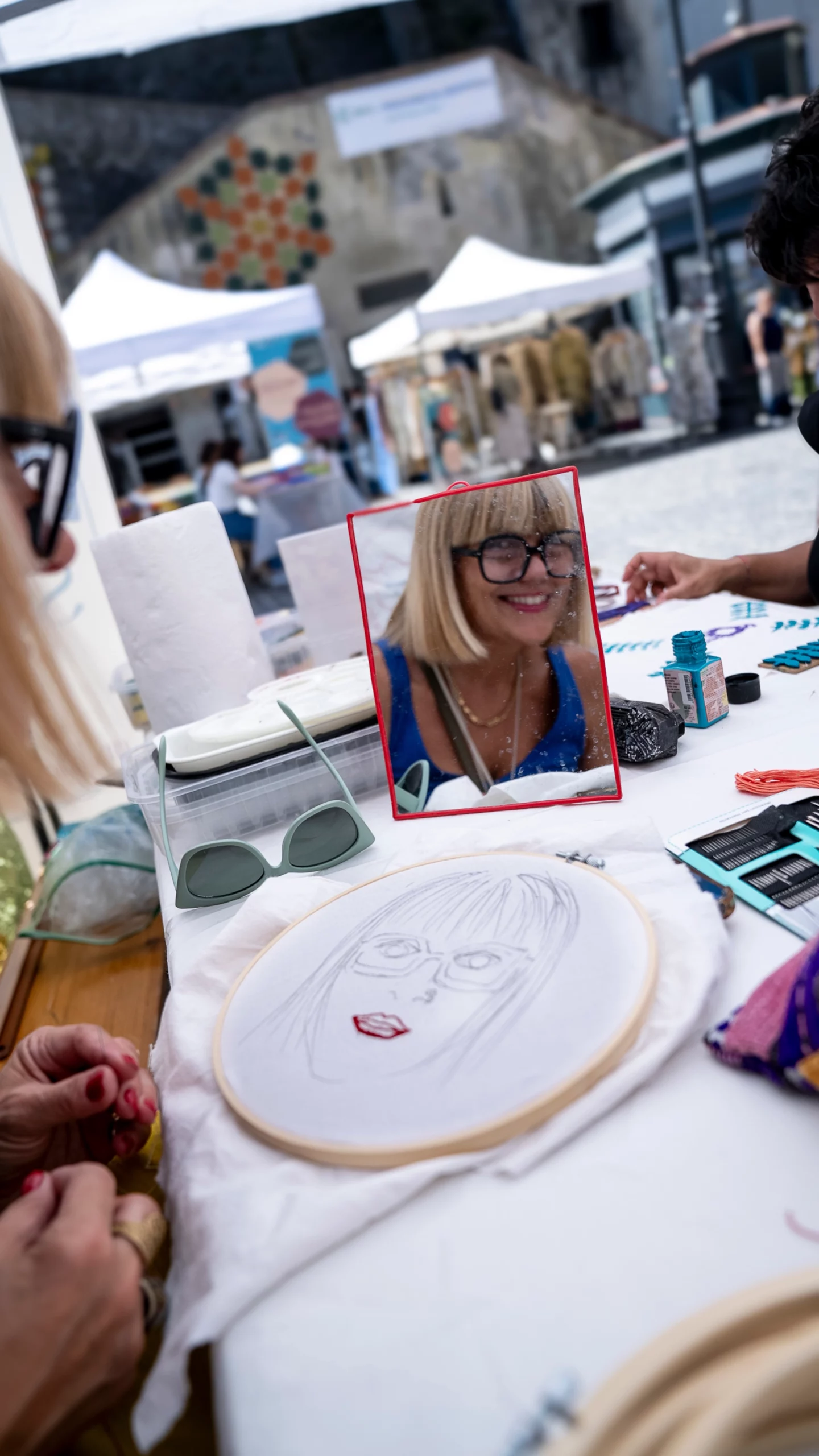 Foto di una donna con di fronte il suo ritratto ricamato